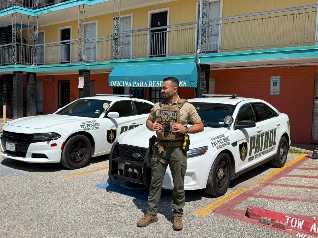Meyer Defense Houston security officer standing with patrol cars at apartment complex, equipped with advanced private security gear.