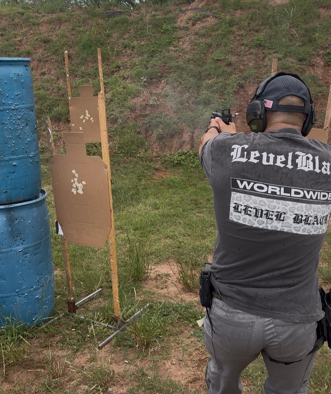 Armed security professional engaging multiple cardboard targets on an outdoor range with a red-dot-equipped duty pistol